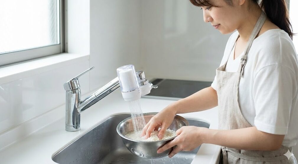 浄水器の水を使って丁寧にお米を研ぐ日本人の女性。お米を美味しく炊くための最初の重要な工程。