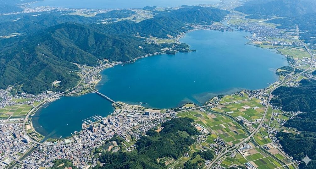 滋賀県の中央に位置する巨大な琵琶湖の航空写真。周囲の山々や街並みと比較してその圧倒的な広さがわかる。