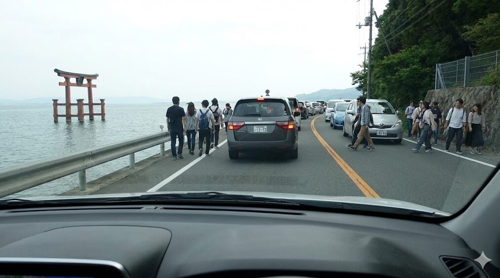 琵琶湖の白鬚神社前で発生している車の渋滞の様子を、車内から撮影した写真。湖中の鳥居が見え、道路を横断する観光客のために車列が停止している。