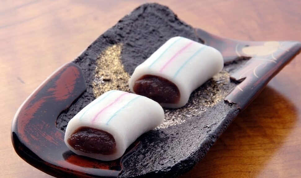 和皿にきれいに並べられた名物「糸切餅」。白い餅の表面には青と赤の線が入っており、断面からはこし餡が見える。