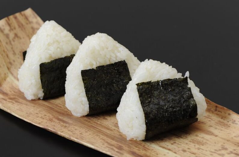 竹ざるに盛られた美味しそうなみずかがみのおにぎり。冷めても美味しいという特徴を伝えるピクニック風の写真。