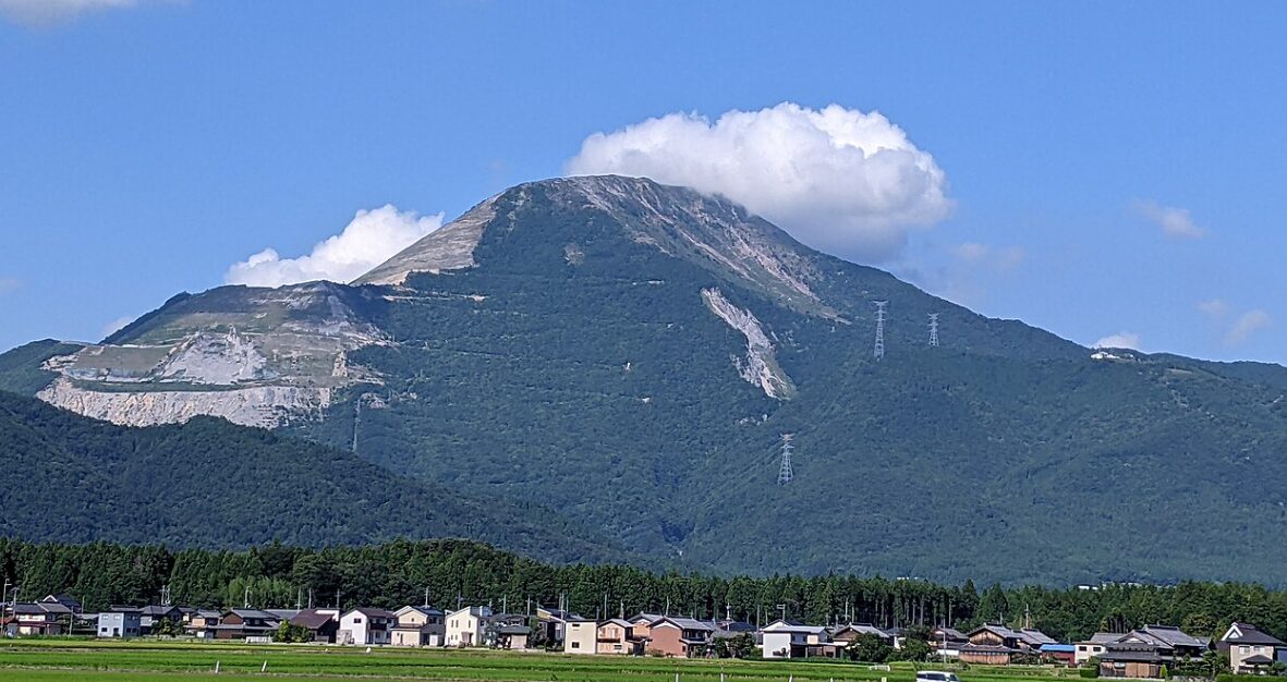滋賀県の伊吹山の遠景写真。山肌の広範囲が赤茶けて露出し、深刻なはげ山化が進行している様子。